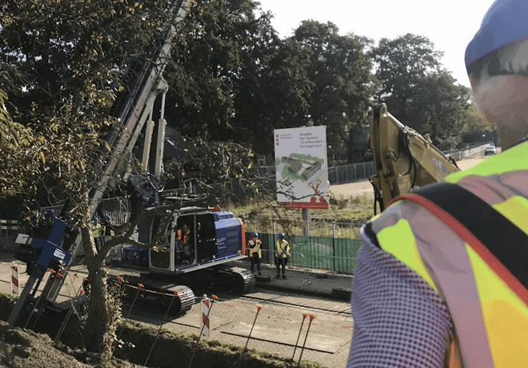 Bouwplaats met graafmachine en werknemer in veiligheidsvest