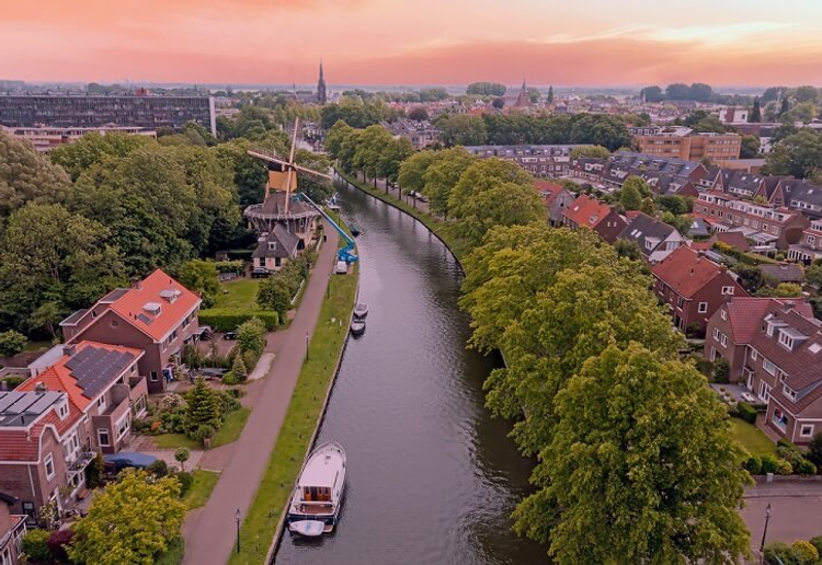 Luchtfoto van Nederlandse stad met gracht, windmolen en woonwijken