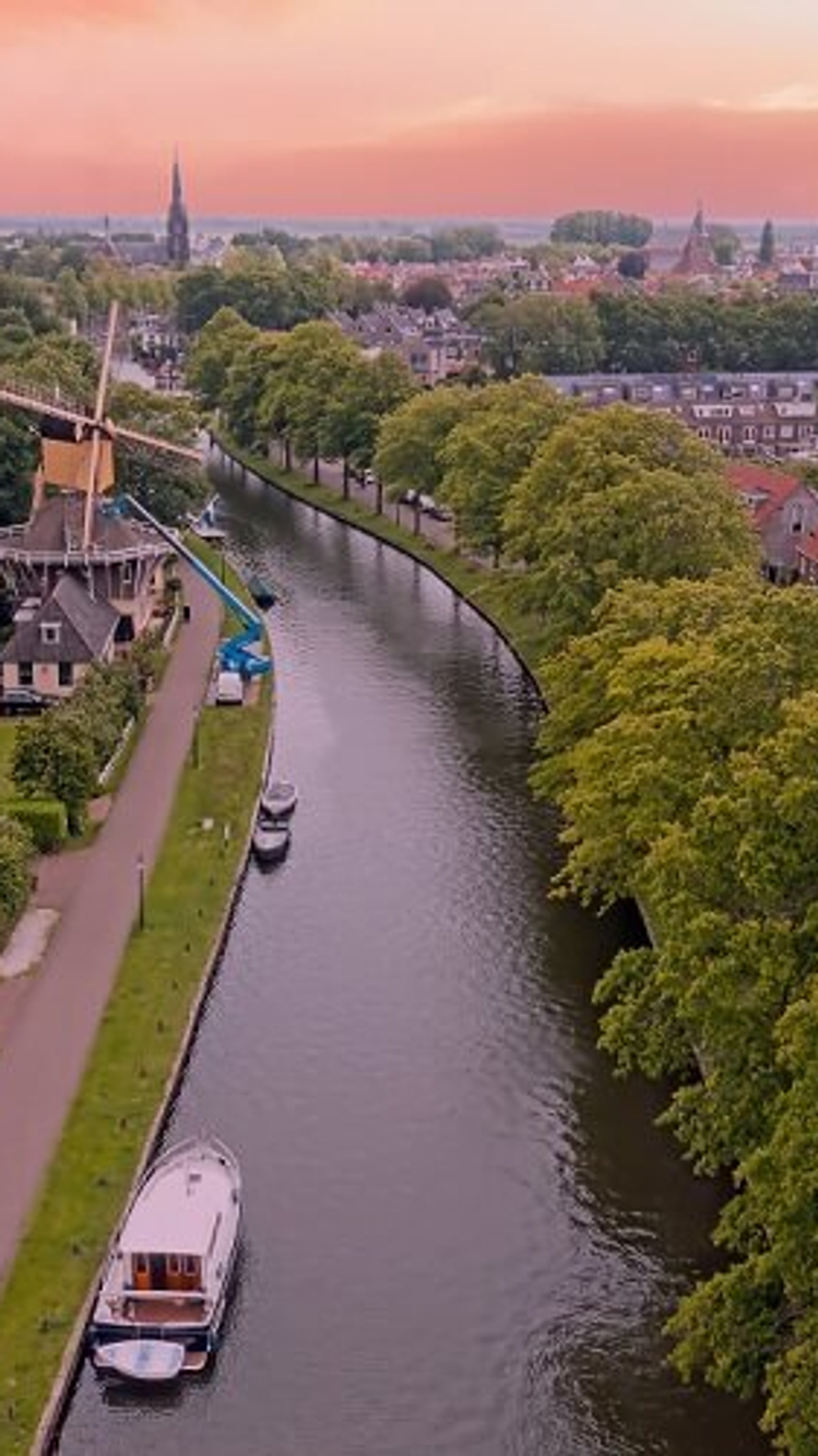 Luchtfoto van Nederlandse stad met gracht, windmolen en woonwijken