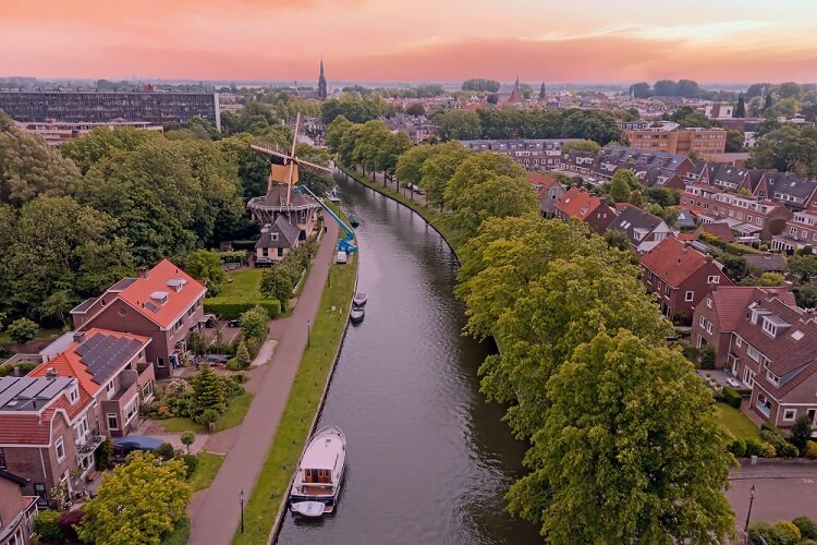 Luchtfoto van Nederlandse stad met gracht, windmolen en woonwijken