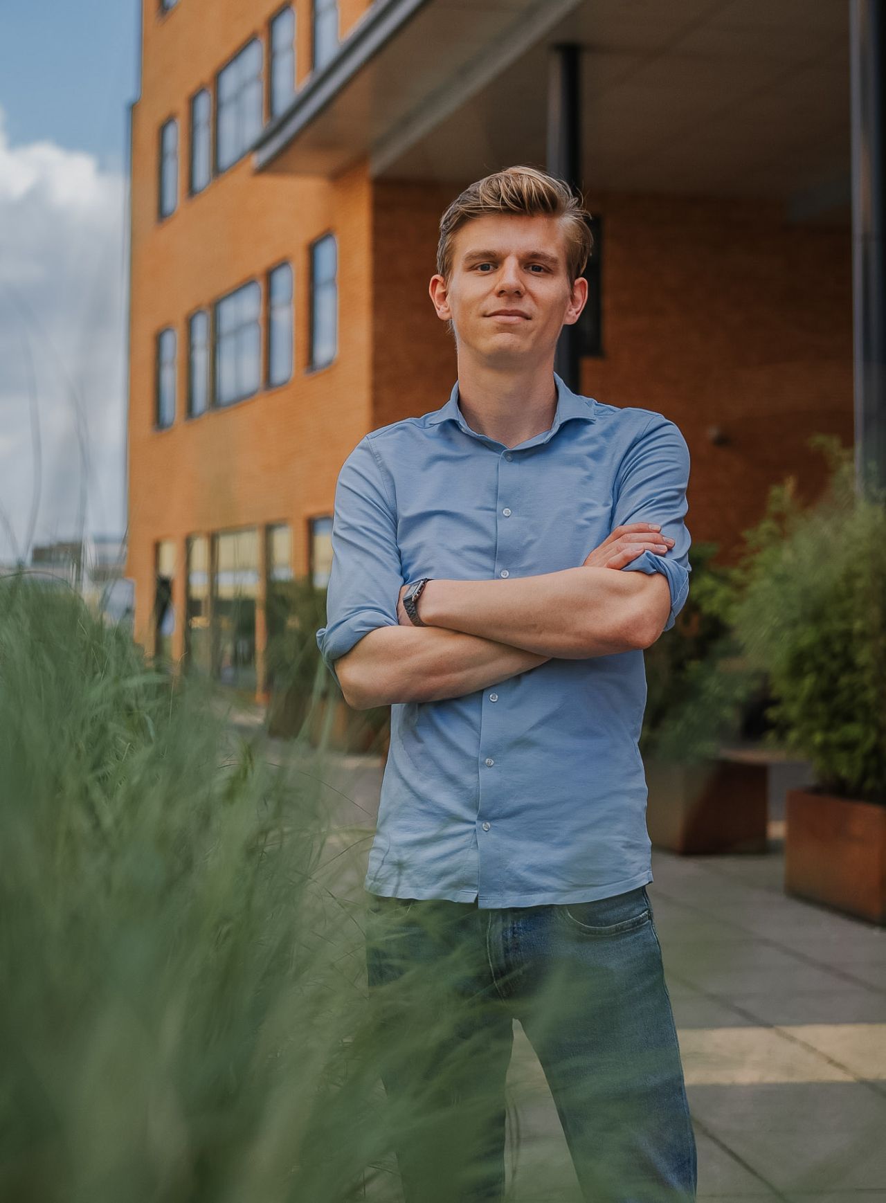 Man met blond haar, met zijn armen over elkaar geslagen voor het Team EIFFEL gebouw met blauw overhemd tot zijn ellebogen opgestroopt en spijkerbroek