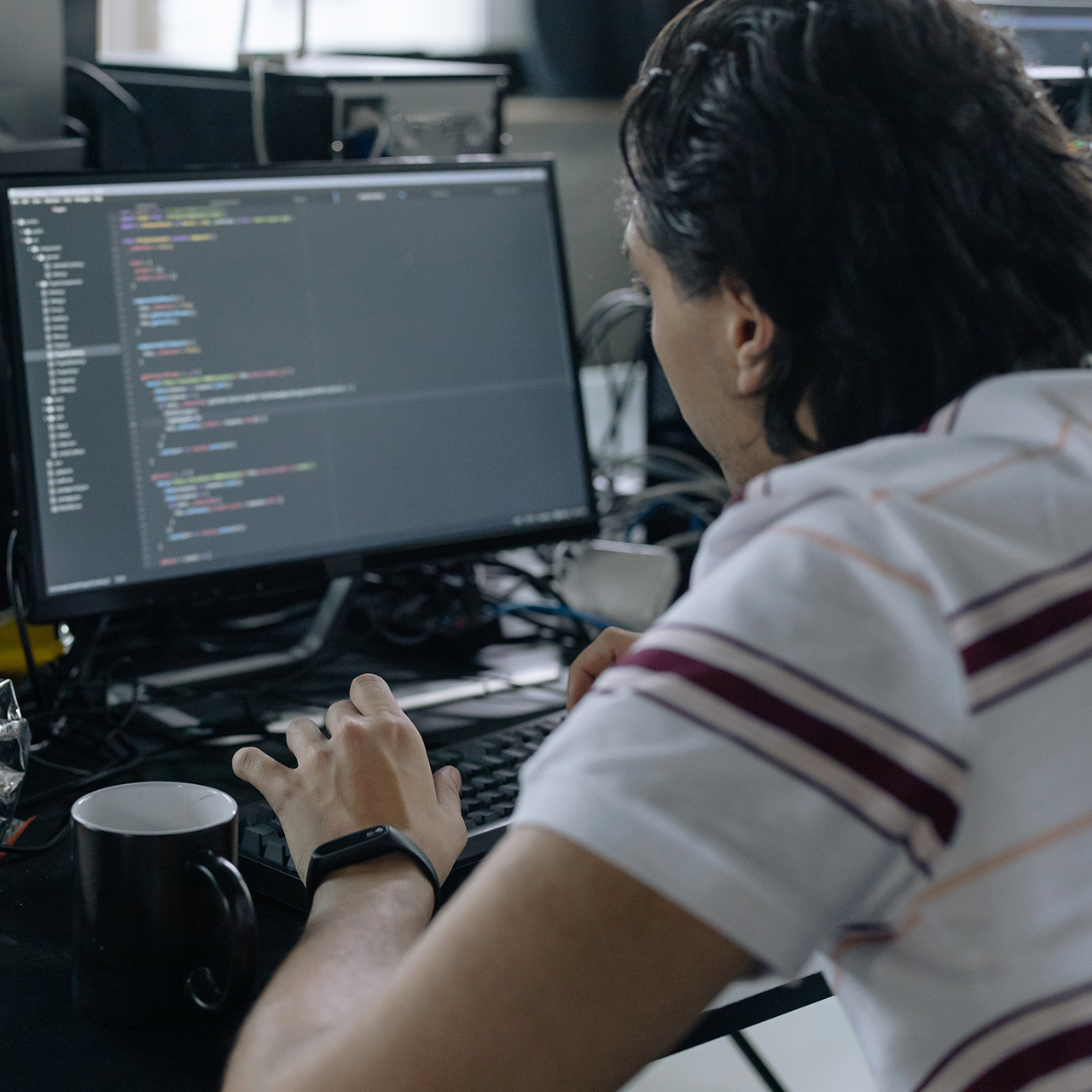 Man werkt aan computerscherm met kleurrijke code en data visualisaties