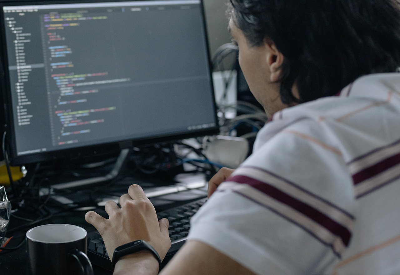 Man werkt aan programmeercode op computerscherm in een kantooromgeving