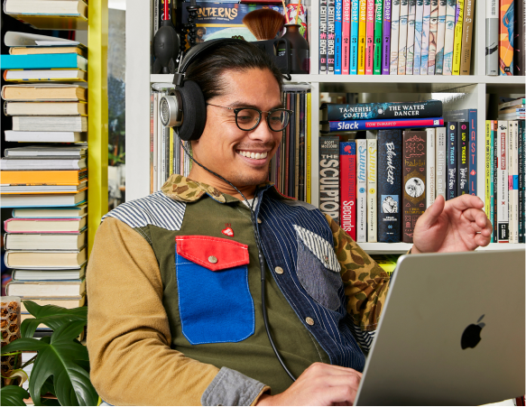 A person wearing headphones and looking at a laptop.