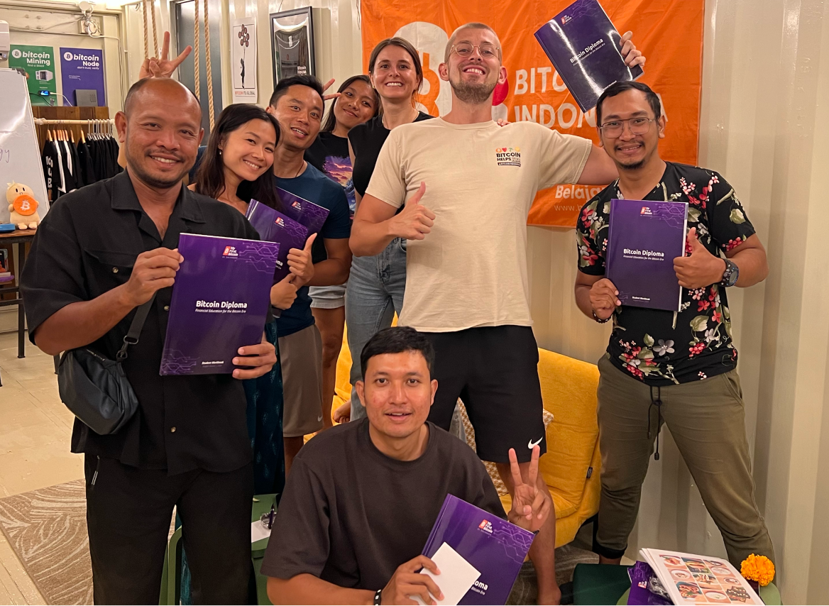 A group of smiling people pose holding pamphlets with purple covers.
