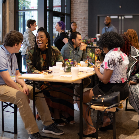 A group of people sit laughing at a table.
