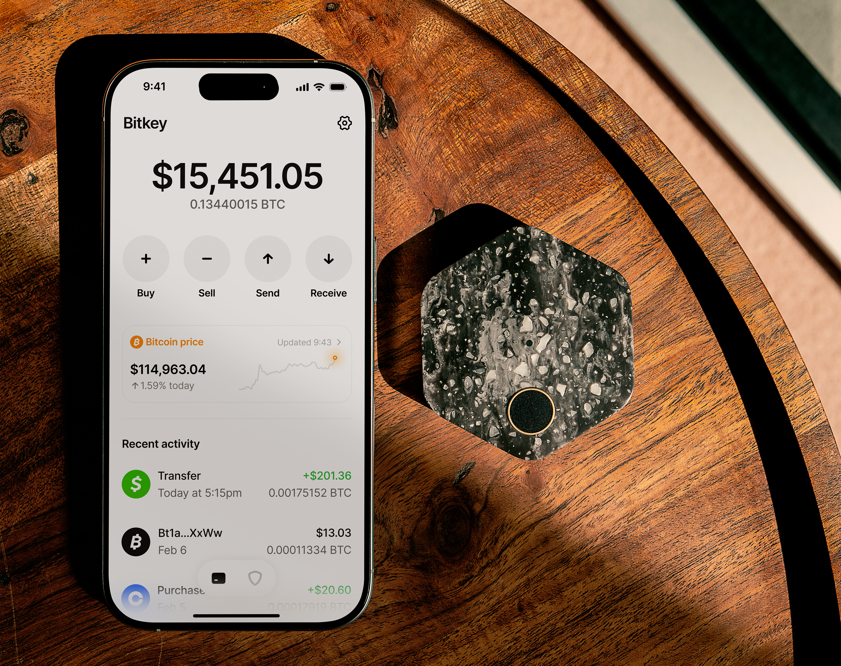 bitkey product ui showing wallet home screen on mobile device next to bitkey device