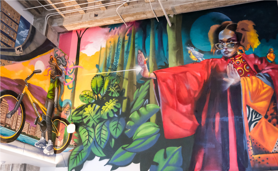 Mural portraying a figure shooting a beam of light at a second figure on a bicycle.