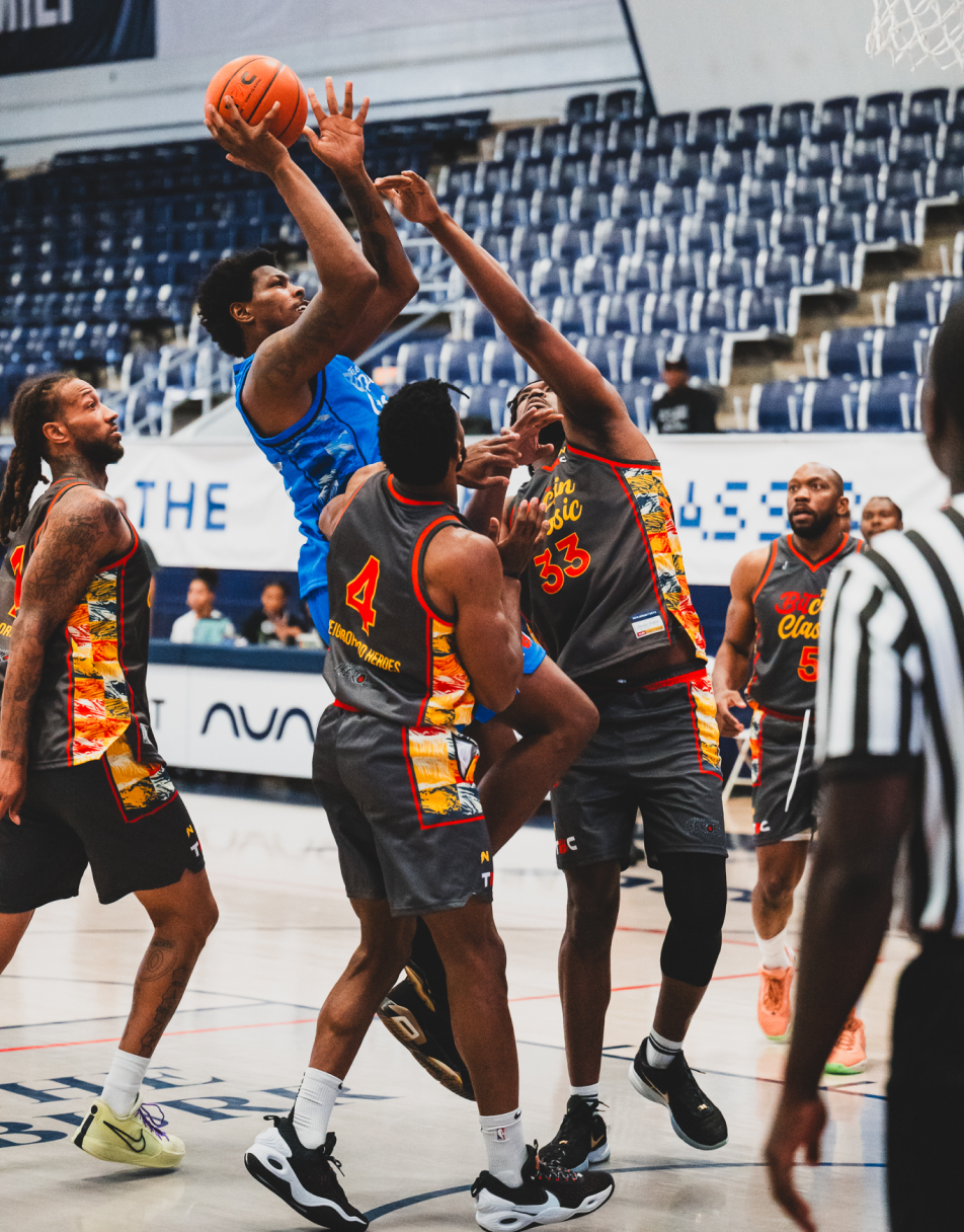 A group of people playing basketball jostle each other for the ball.