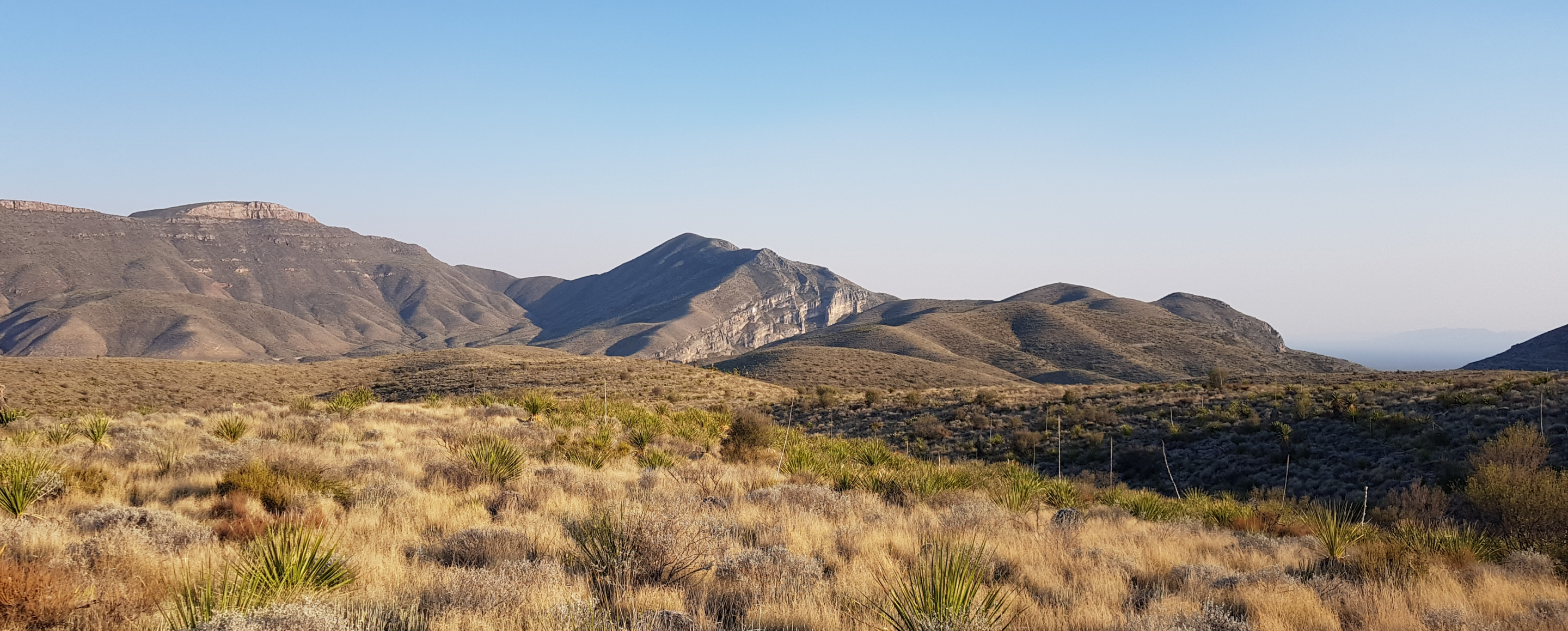 A landscape of a desert with mountains and blue sky.