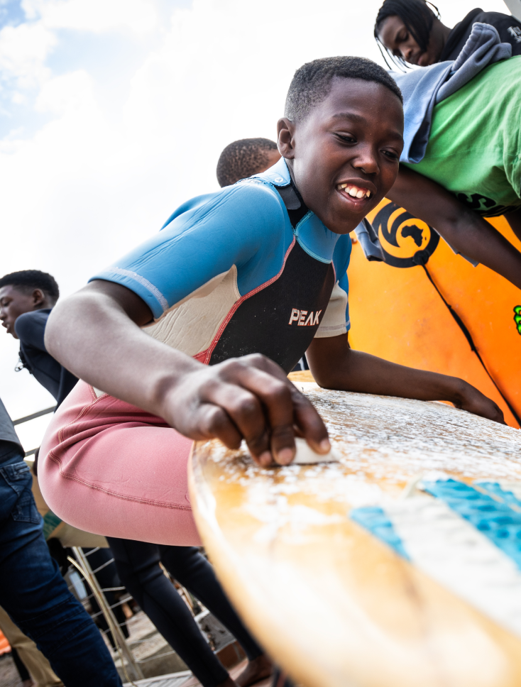 A child waxes a surfboard.