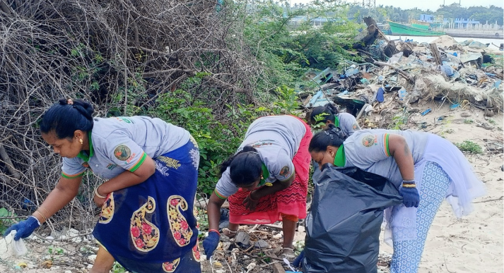 A group of people cleaning up trash on a beach.