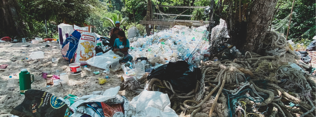 People sitting on the ground with a pile of plastic bottles and ropes.