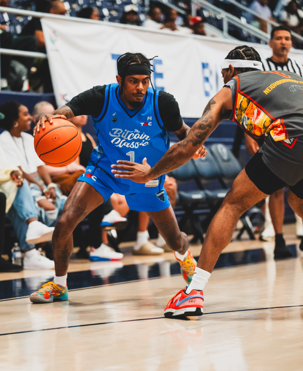 Two people play basketball on an indoor court.