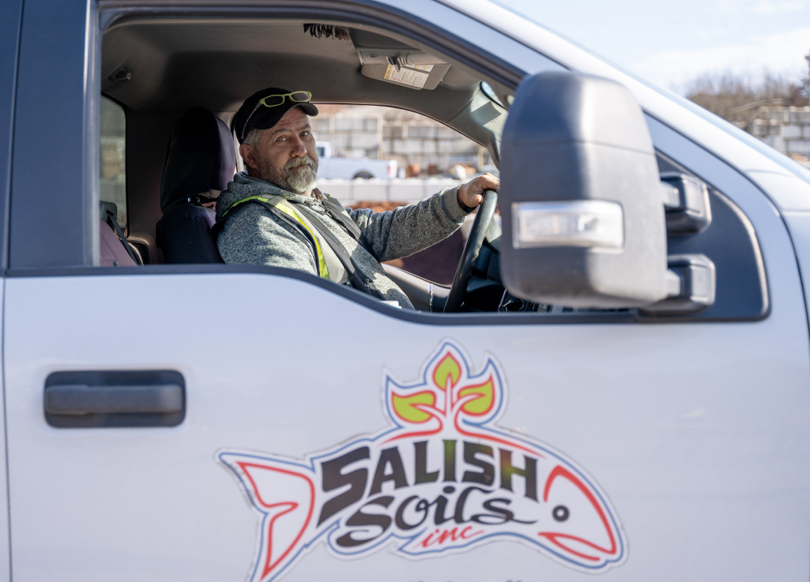 A person wearing a black hat sits in the driver's seat of a work vehicle.