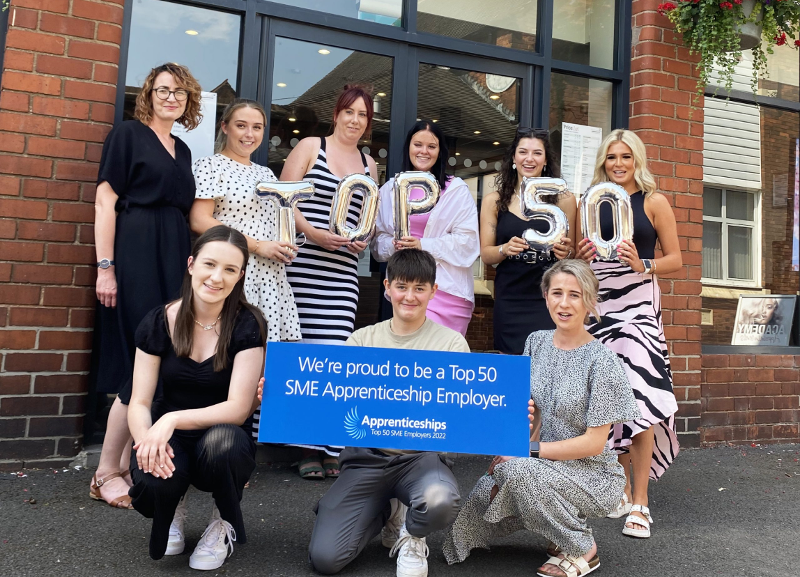A group of people pose for a photograph outside a brick building.