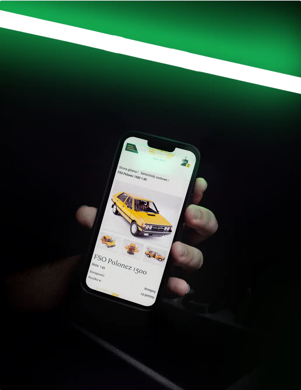 Sklep internetowy z samochodami kolekcjonerskimi na telefonie trzymany w ręce i zielonym neonowym tle