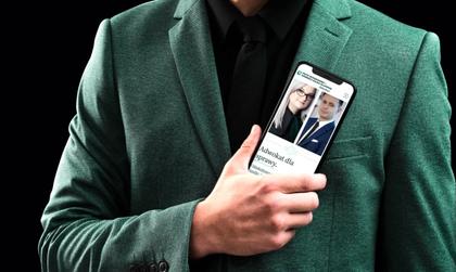 Mężczyzna w zielonym garniturze, który w ręku trzyma smartfona, na którym wyświetla się strona www kancelarii adwokackiej