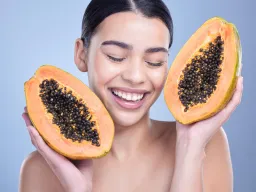 Woman holding fresh papaya smiling, symbolizing natural fruit enzyme peel benefits – Ormedic Lift by Image Skincare in Berlin.
