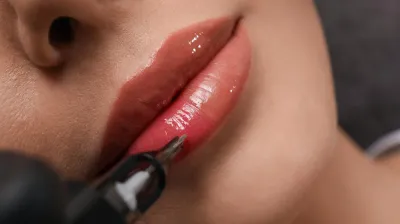 Nahaufnahme eines Lippenpigmentierungsverfahrens in Berlin, bei dem ein natürlicher Lippenfarbton mit einer kosmetischen Tätowiermaschine aufgetragen wird