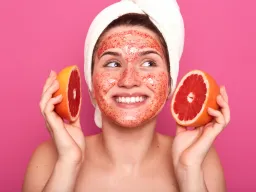 Woman with grapefruit face mask smiling after fruit acid peeling facial treatment in Berlin