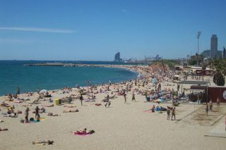 Lively Platja de la Mar Bella on a busy summer day