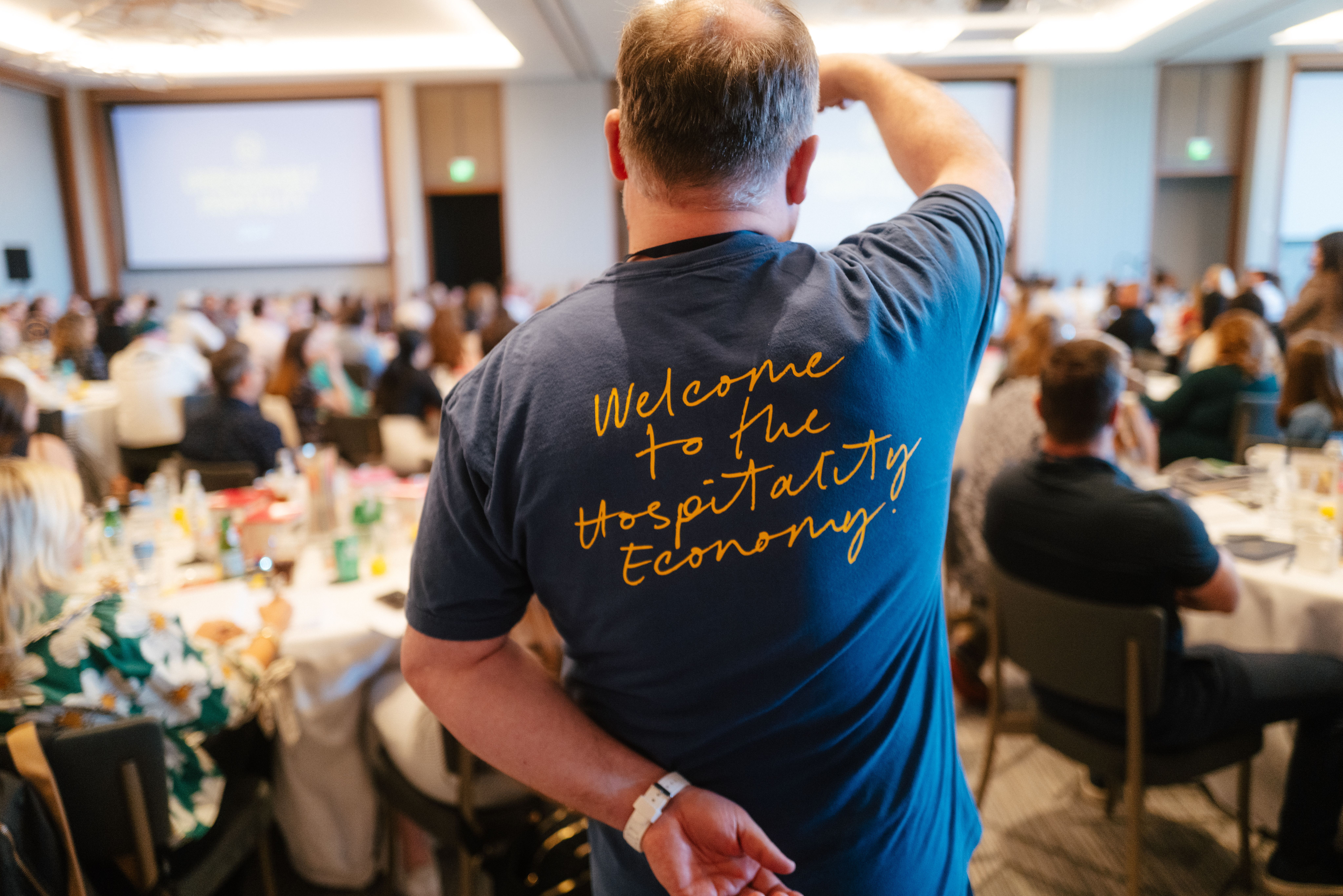 Back of team member's shirt at The Summit. Shirt says: Welcome to the Hospitality Economy