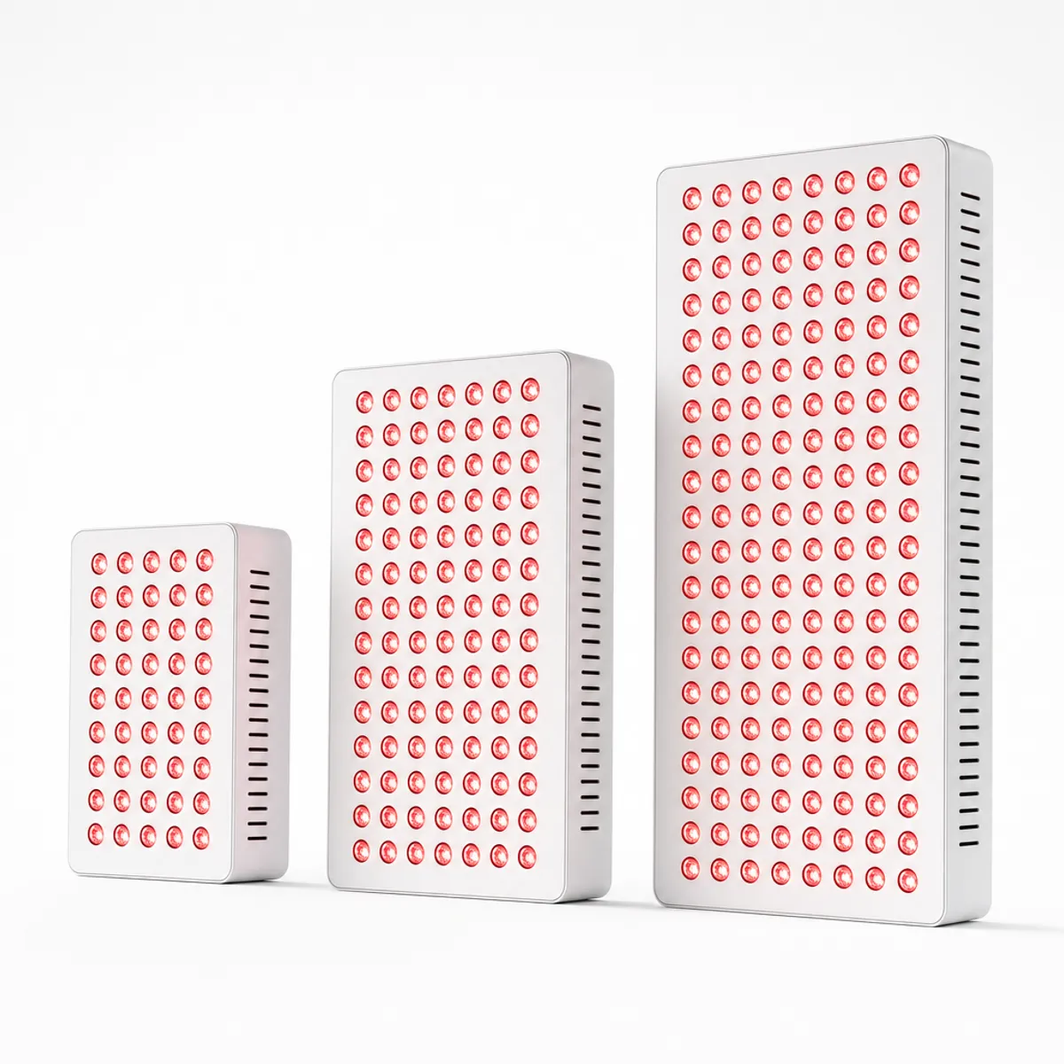 Three red light therapy panels of different sizes displayed side by side in size progression from small to large, professional product photography style, clinical white background, LED arrays visible on each panel showing increasing coverage area, clean modern medical device aesthetic, sharp focus, commercial quality lighting