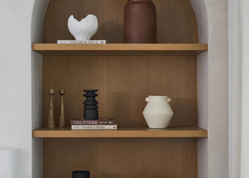 An arched niche in white oak, shelves holding ceramics