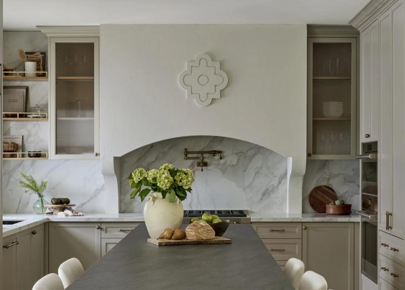 A marble arch cut over the range, greenery on the counter beneath