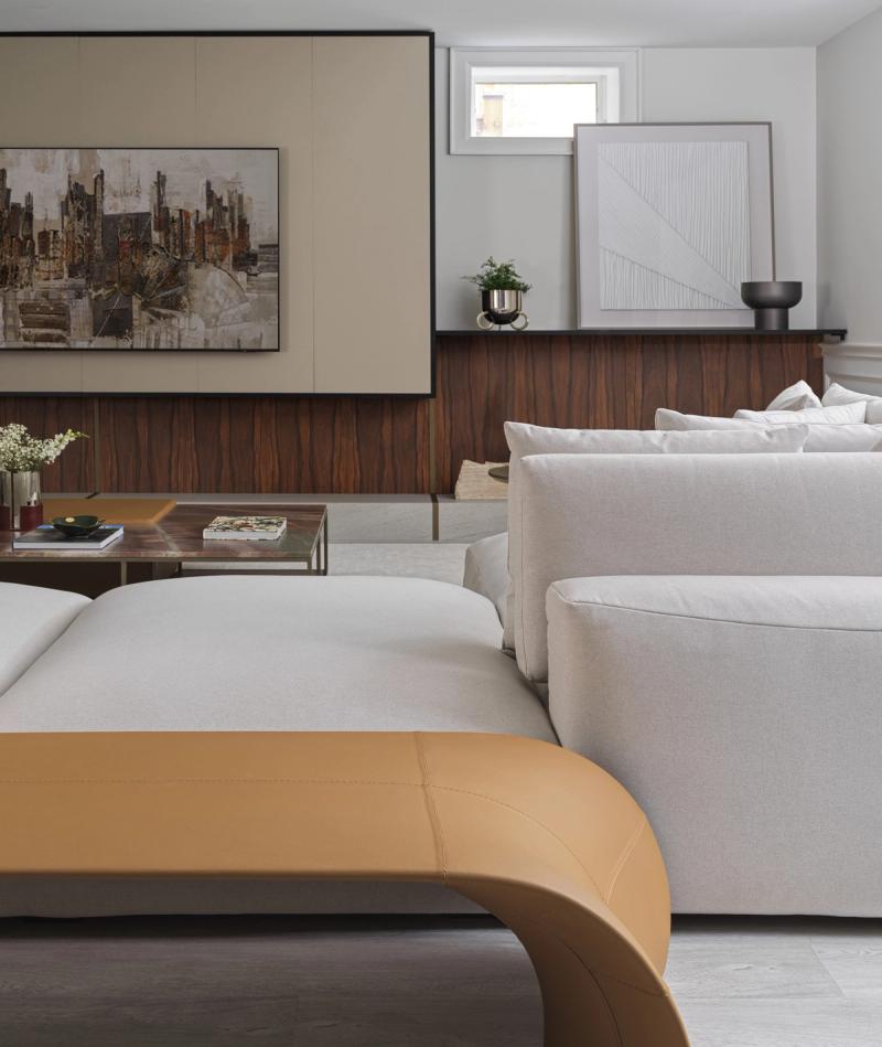 A basement living room, art hung on a walnut panelled wall above the sofa