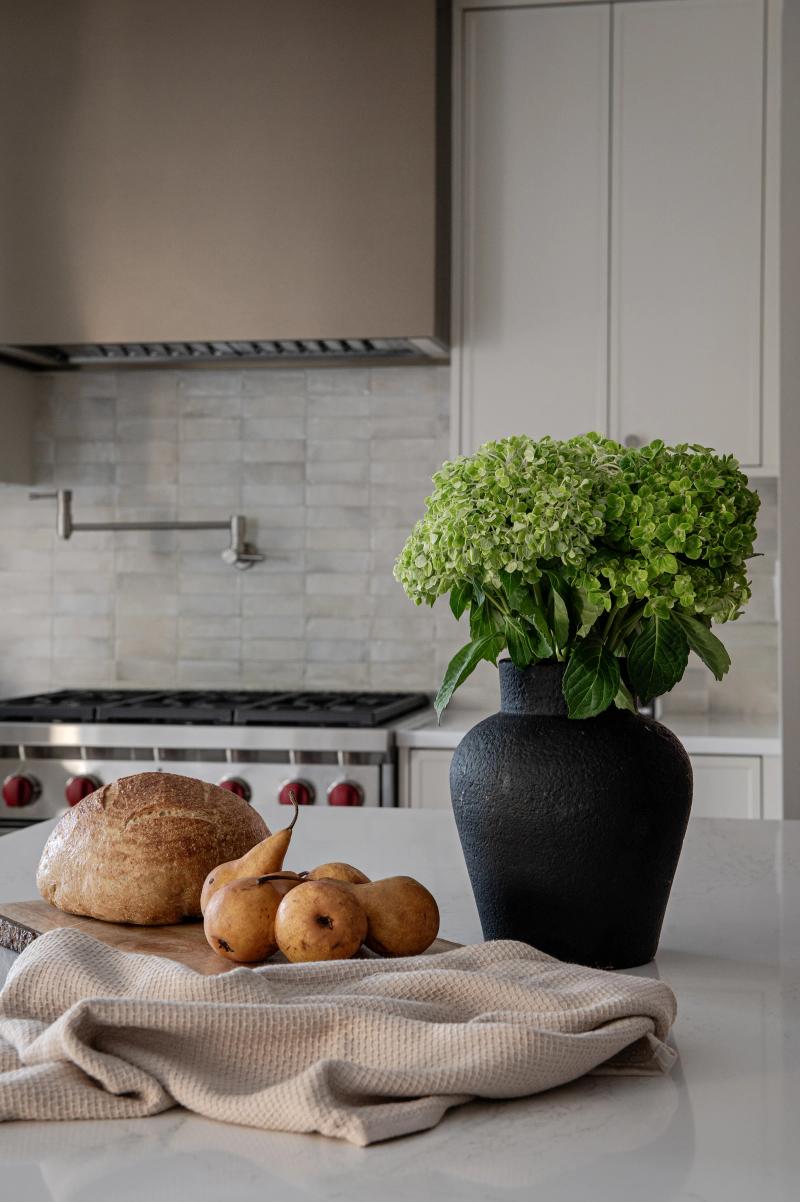 A range set into a marble backsplash, bread and greenery on the counter
