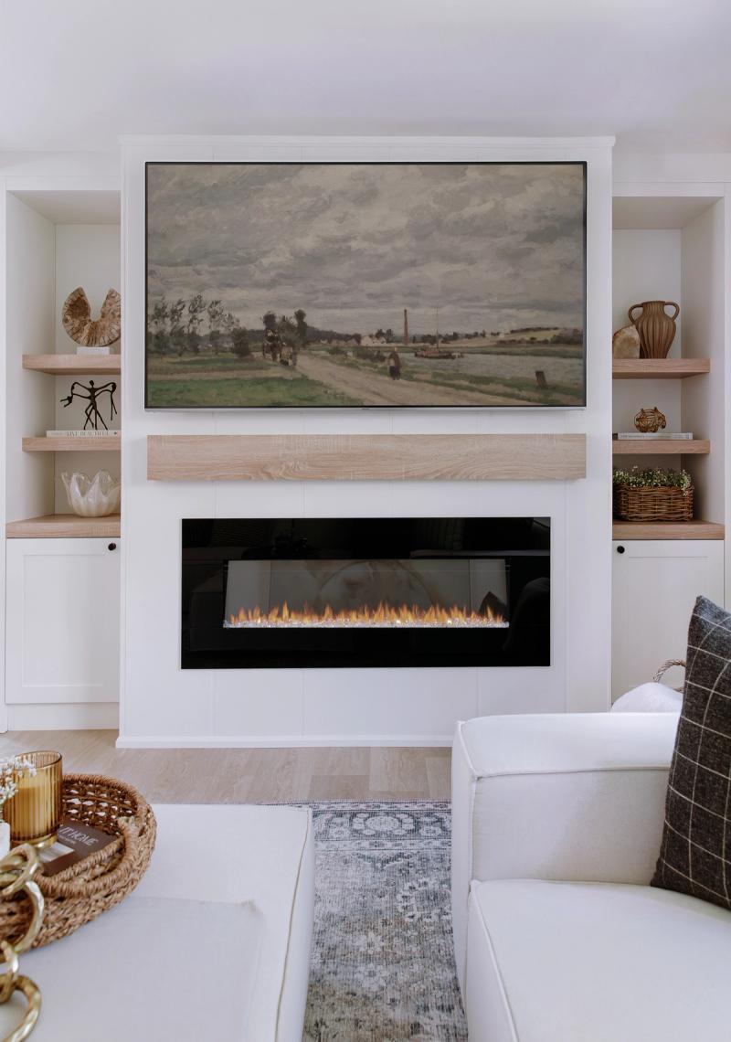 A living room fireplace under a wide landscape painting