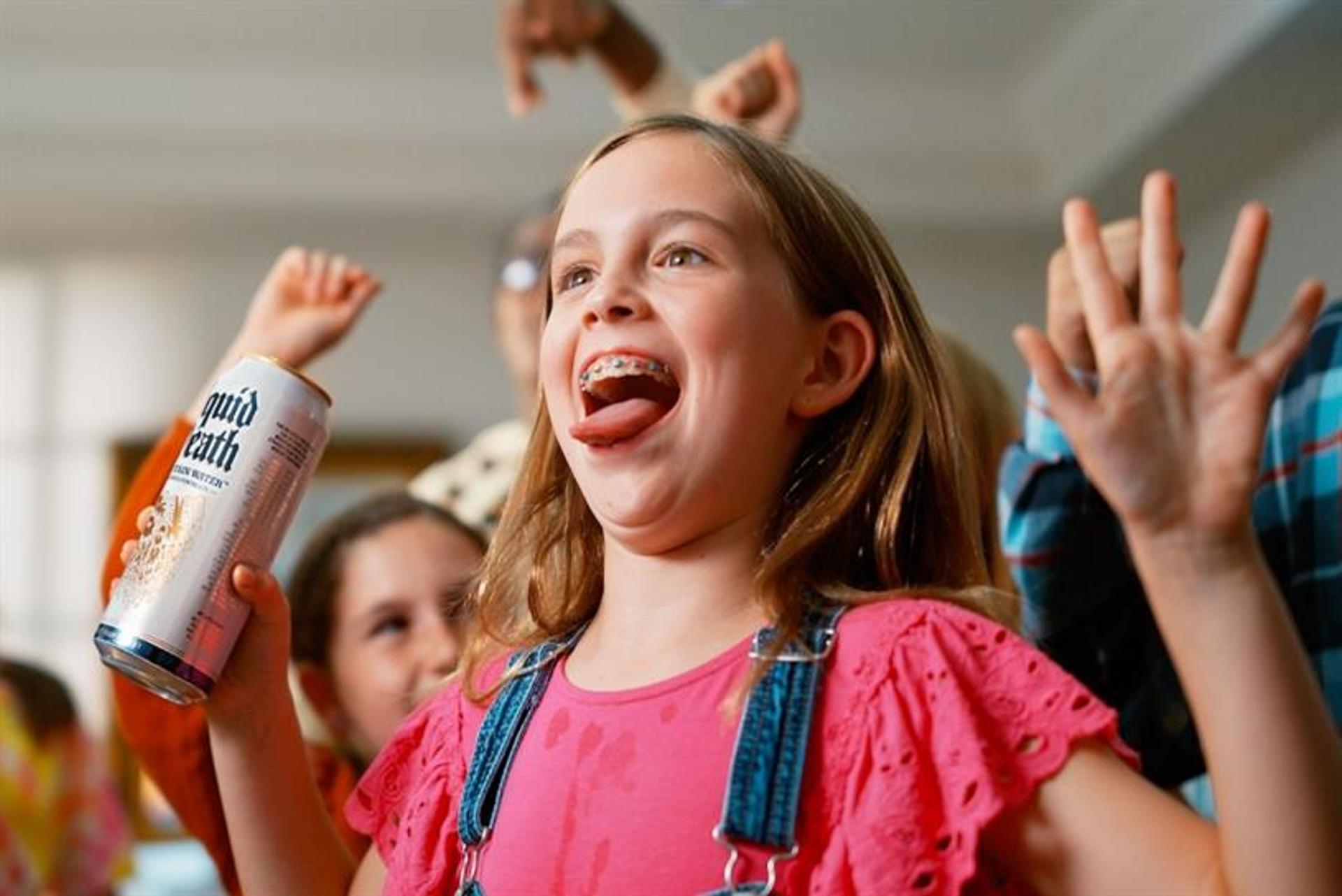 A young girl wearing braces smiling and holding a can of Liquid Death water