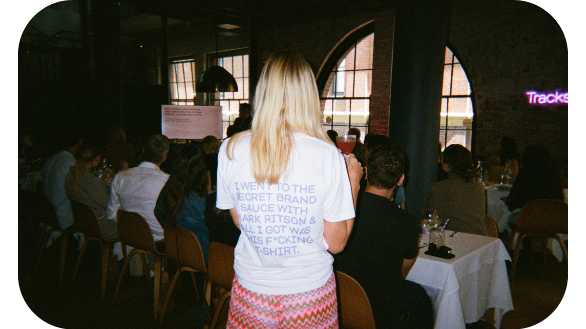 A woman wearing a t-shirt that says 'I went to the secret brand sauce with Mark Ritson', symbolizing her attendance at a marketing event where Mark Ritson shared insights on brand strategy and marketing