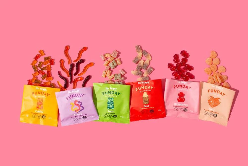 lineup of funday sweets packets with candy coming out of them on a pink background