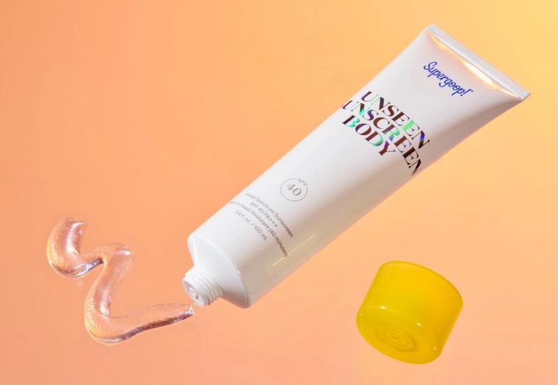supergoop sunscreen on orange gradient background with squirt of sunscreen
