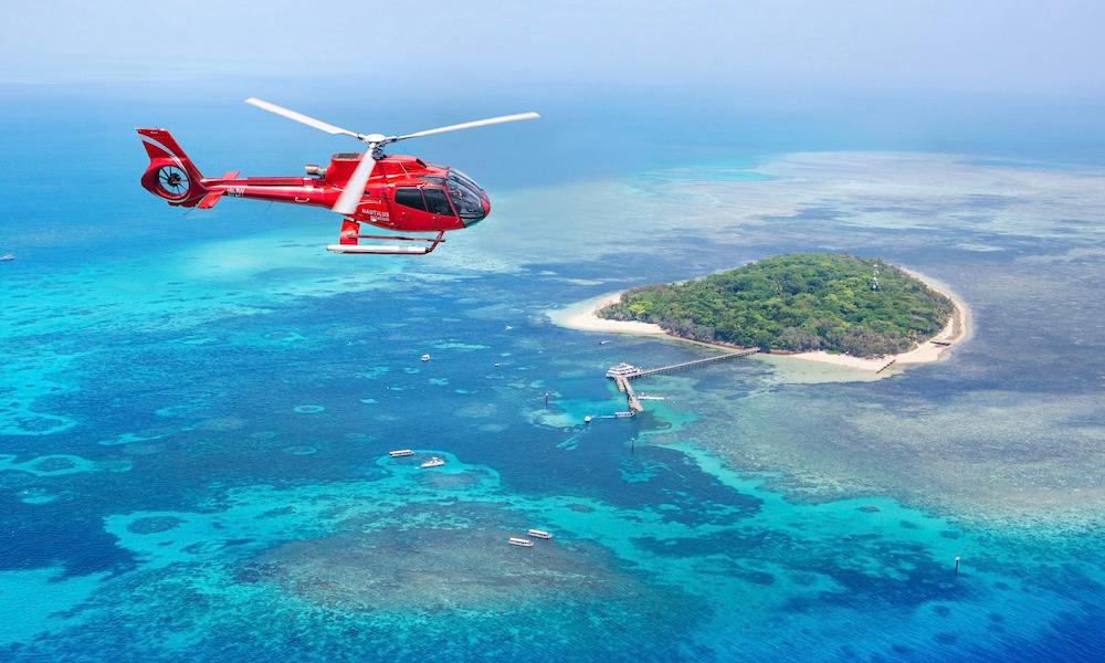 A red helicopter representing Big Red Group's expansive reach, flying over a small island in the ocean, symbolizing their influence in the vast marketing landscape