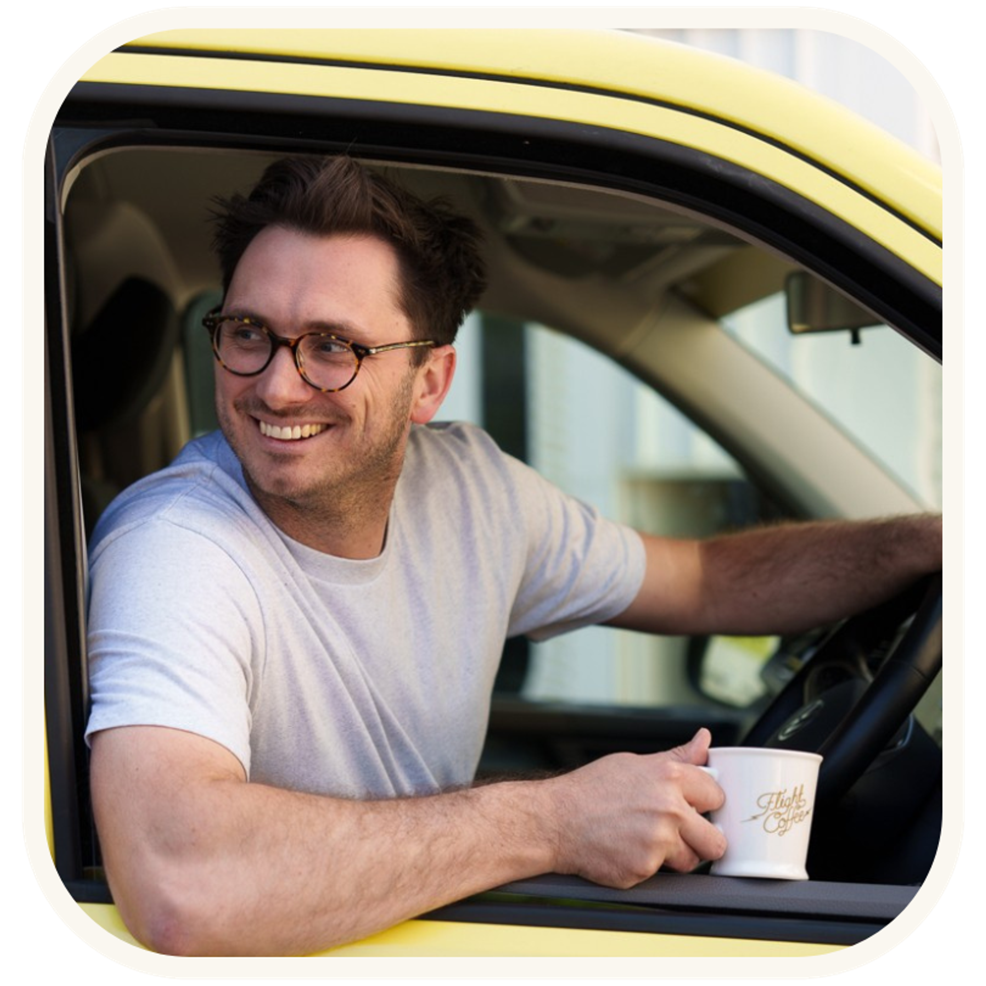 A man in a yellow van, representing Flight Coffee, holding a can of their Oat Milk Flat White coffee, ready to enjoy it. This image is part of a coffee advertising campaign.