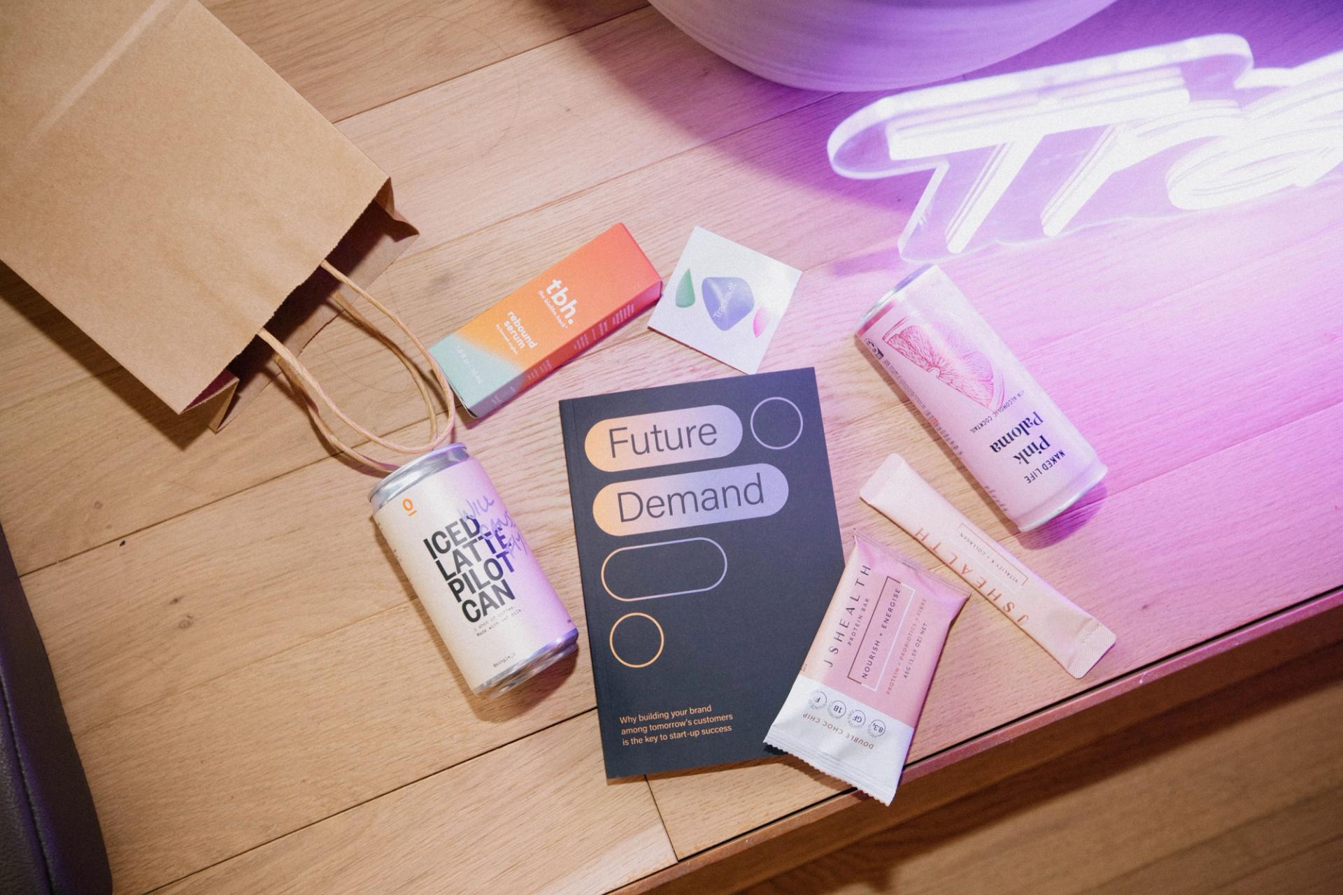 A table with a book titled 'Future Demand', a can of soda, and a bag, symbolizing the discussion of future demand in brand marketing strategies.