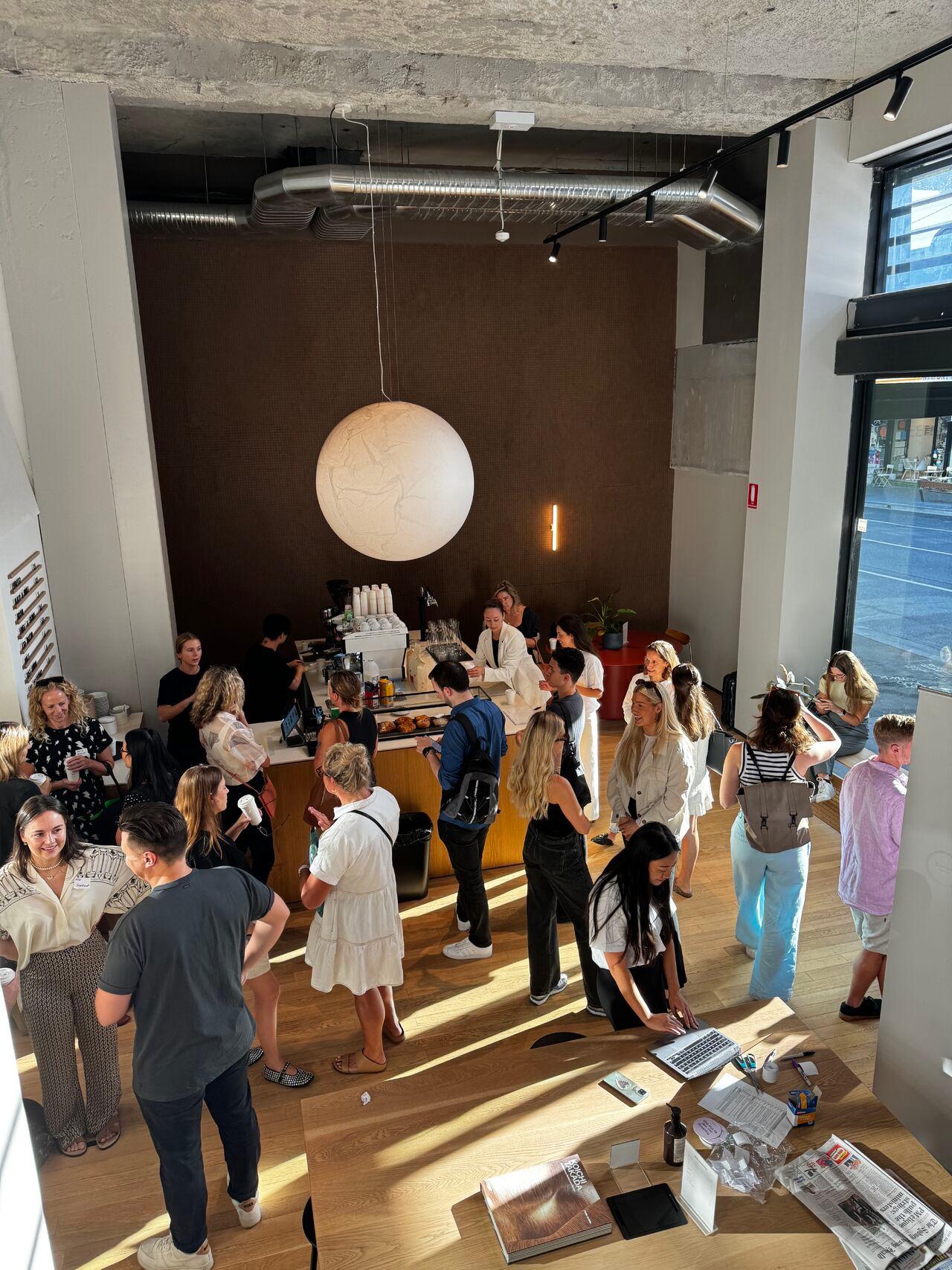 A group of marketing professionals discussing strategies at a Tracksuit event in a room with a large white ball hanging from the ceiling
