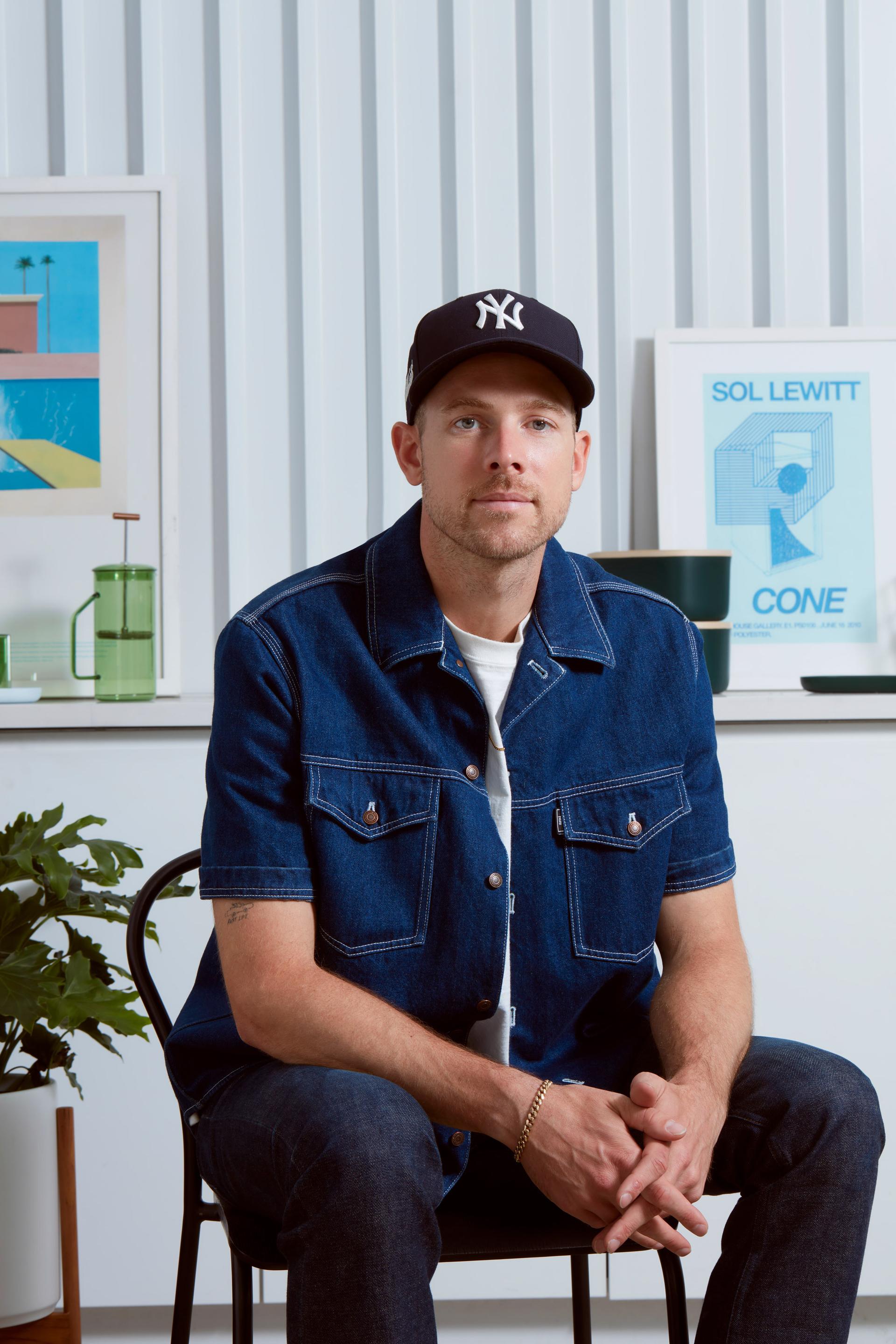 Emmett Shine, the Chief Creative Officer and Co-Founder of Pattern Brands, sitting on a chair while wearing a NY hat