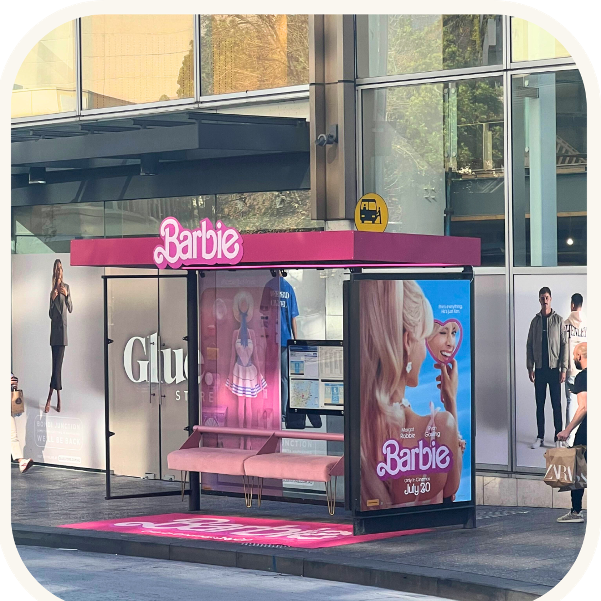 A bus stop featuring a promotional Barbie sign, part of the extensive marketing campaign for the upcoming Barbie movie