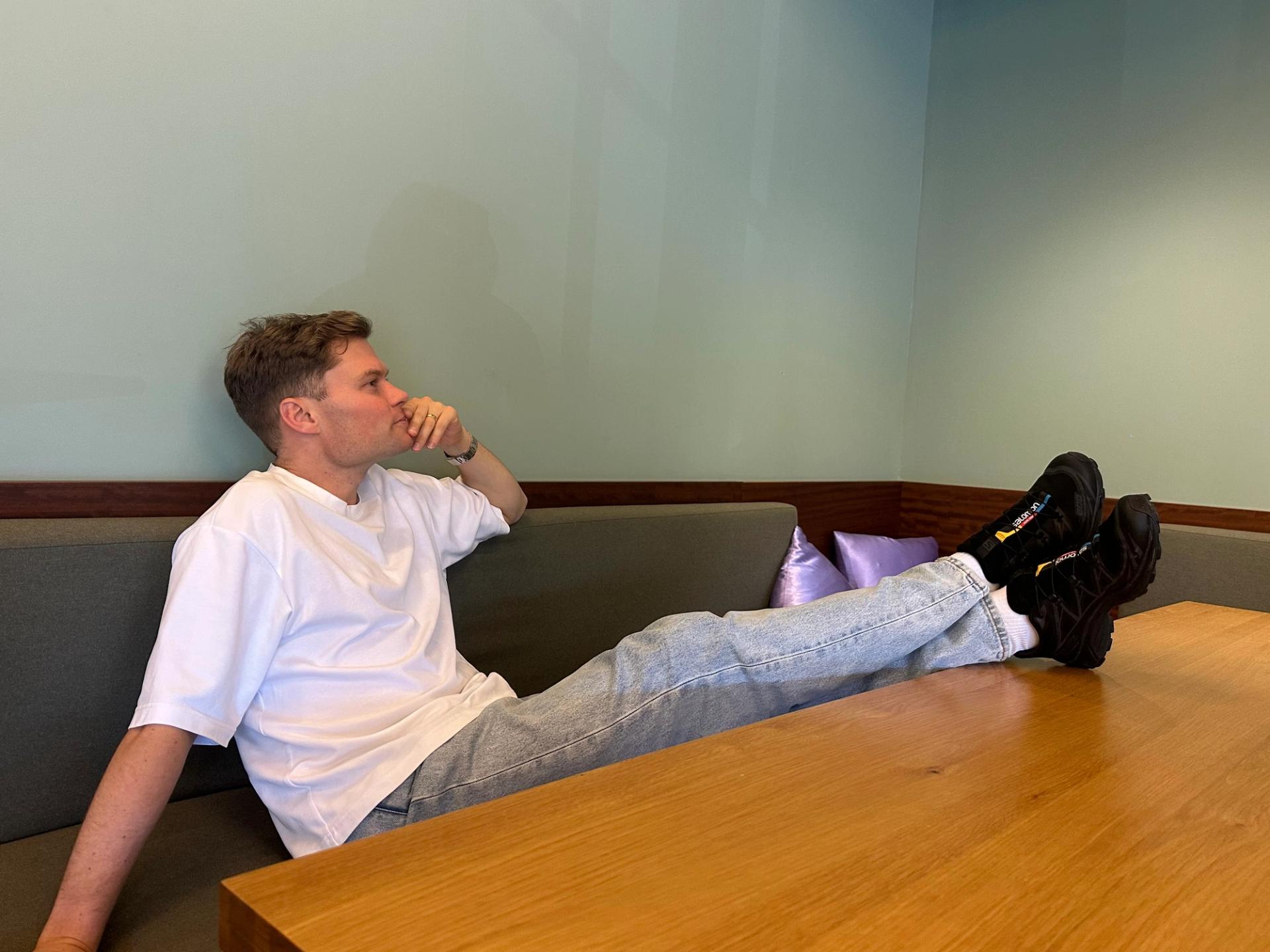 Matt relaxing on a couch with his feet up on a table, showcasing his new black Salomon XT-6 trail shoes