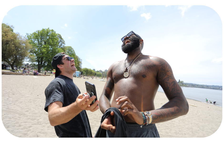 Two men engaging in a conversation on the beach, one without a shirt, symbolizing the personal and authentic connections formed in brand ambassador programs