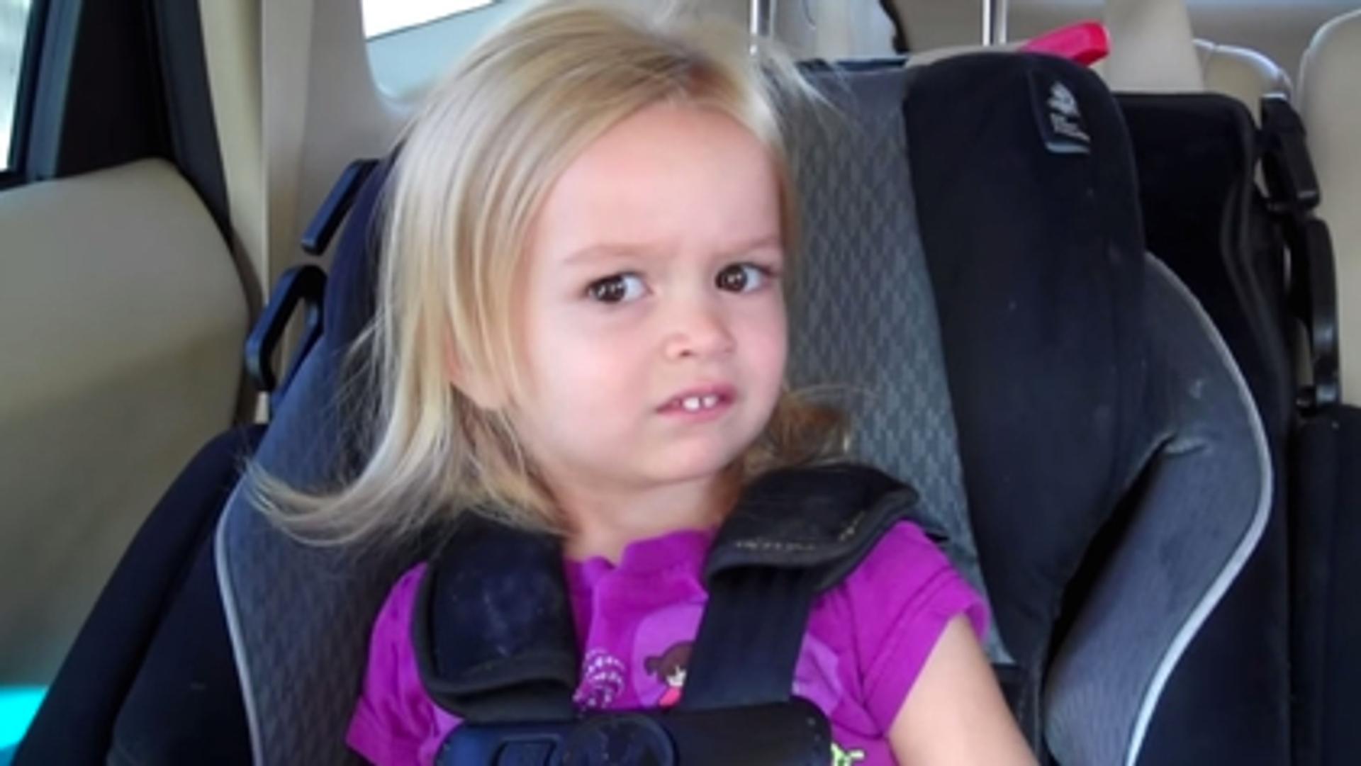 A little girl making a funny face while sitting in a car seat