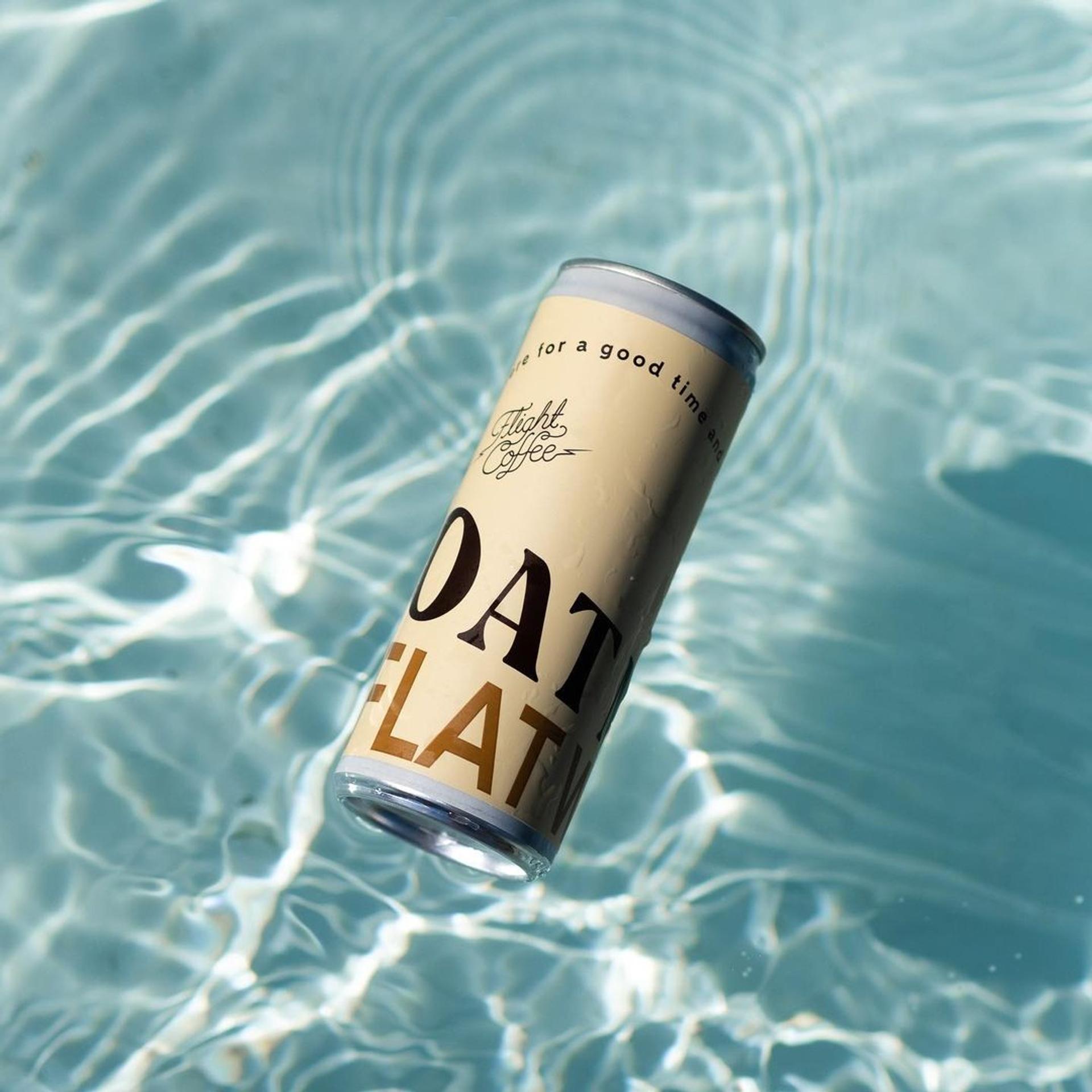 A can of oat flat white is floating in the water.