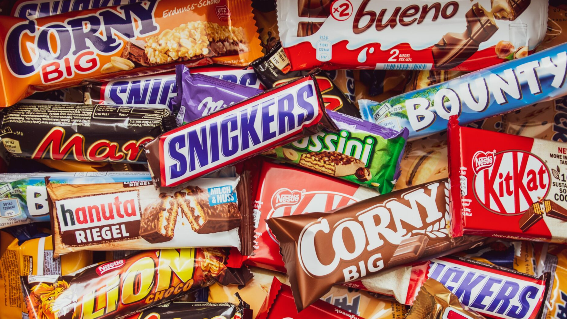 A pile of various candy bars including popular brands like Snickers, Bounty, and KitKat, symbolizing brand awareness in the confectionery market