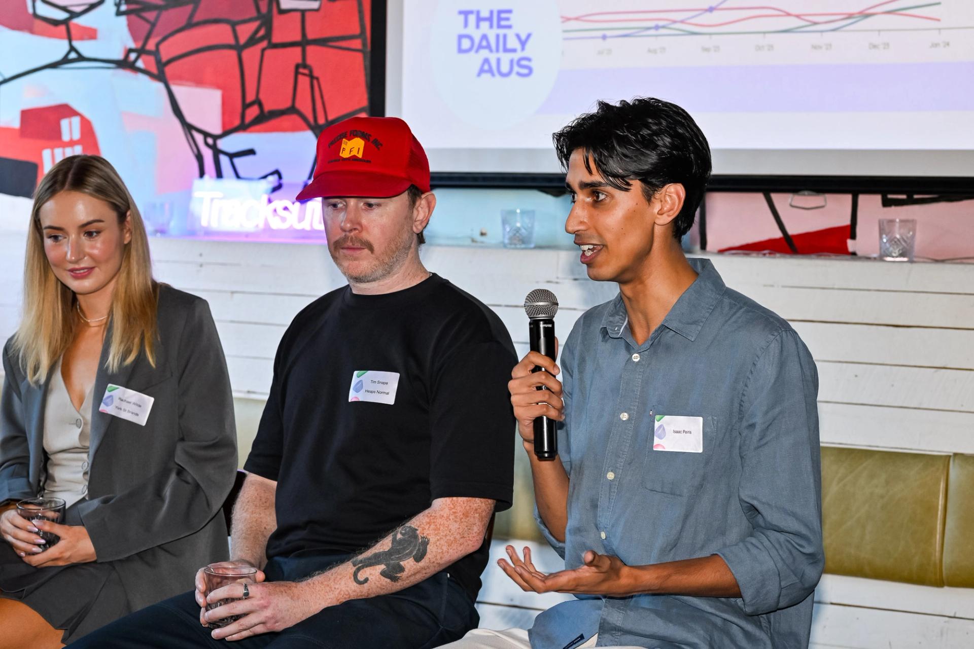 A panel discussion at a Tracksuit event where a group of marketing professionals are sitting on a couch, with one man holding a microphone, discussing marketing strategies and insights for 2024