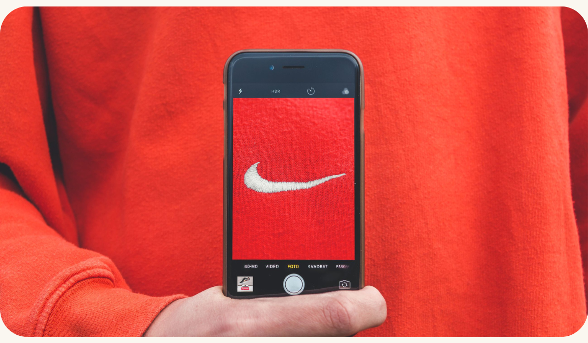 A person capturing a photo of a Nike logo on their mobile phone, symbolizing brand recognition and accessibility